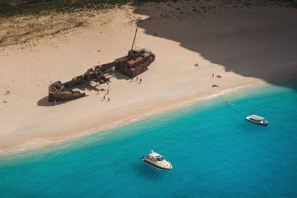Greece yacht charter in crystal blue water docked by the coastline of an island shipwreck. 